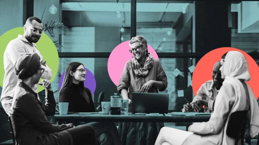 A diverse group of six people sit and stand around a table in a retail office, smiling and talking. Colorful circles are overlaid in the background, creating a lively, collaborative atmosphere.